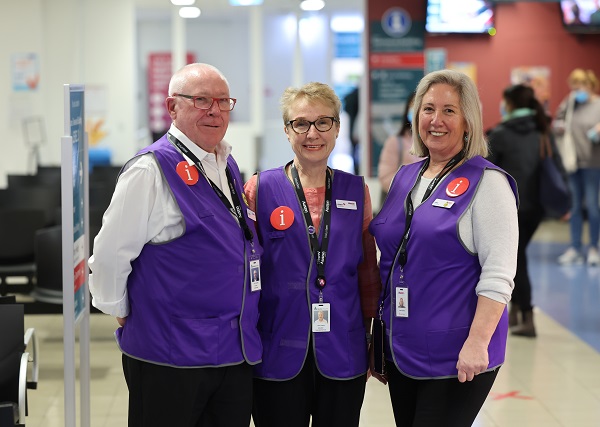 A group of volunteers wearing purple vests, information badges and ID tags.